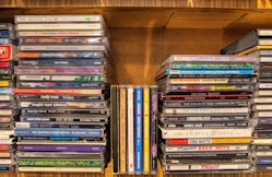 assorted cd case on brown wooden shelf