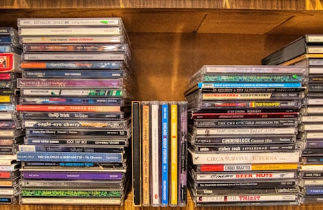 assorted cd case on brown wooden shelf