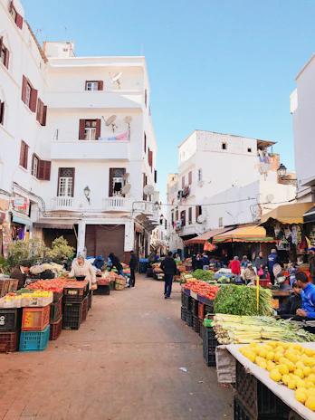 A vibrant street market in Andalusia bustling with locals and colorful produce under a bright blue sky.