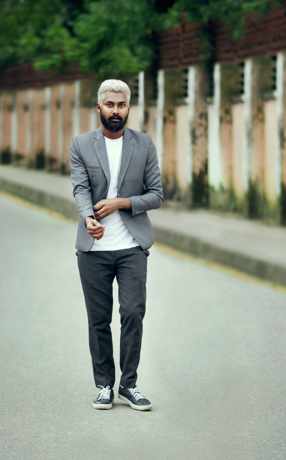 man in gray suit standing on gray concrete road during daytime