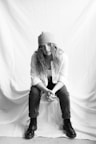 woman in white long sleeve shirt and black pants sitting on white textile