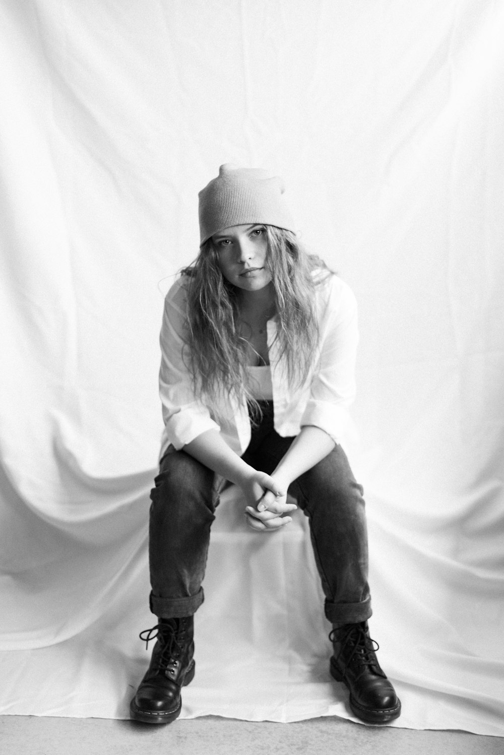 woman in white long sleeve shirt and black pants sitting on white textile