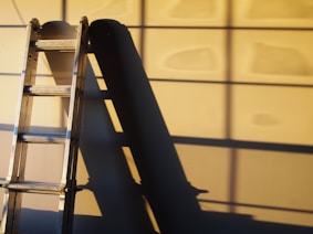 black metal ladder leaning on white wall