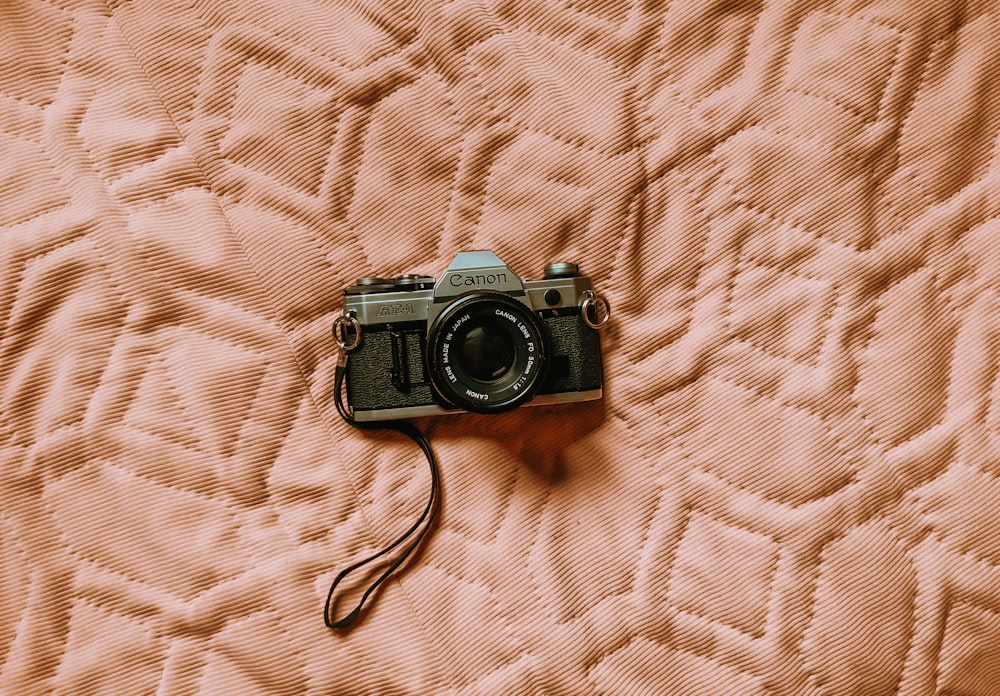 black and silver dslr camera on white textile