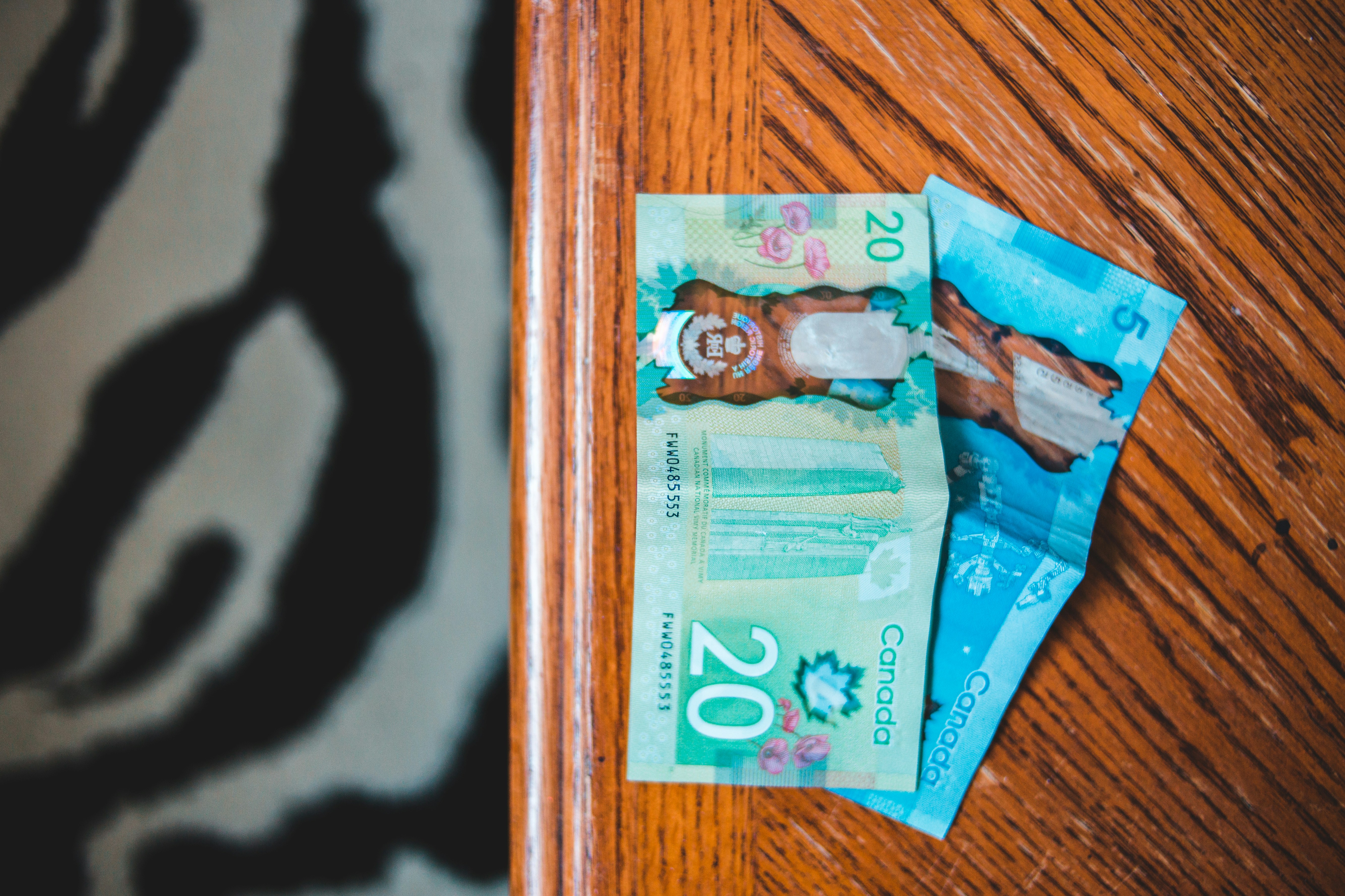 Canadian twenty-dollar polymer bills on a wooden table for study permit budgeting