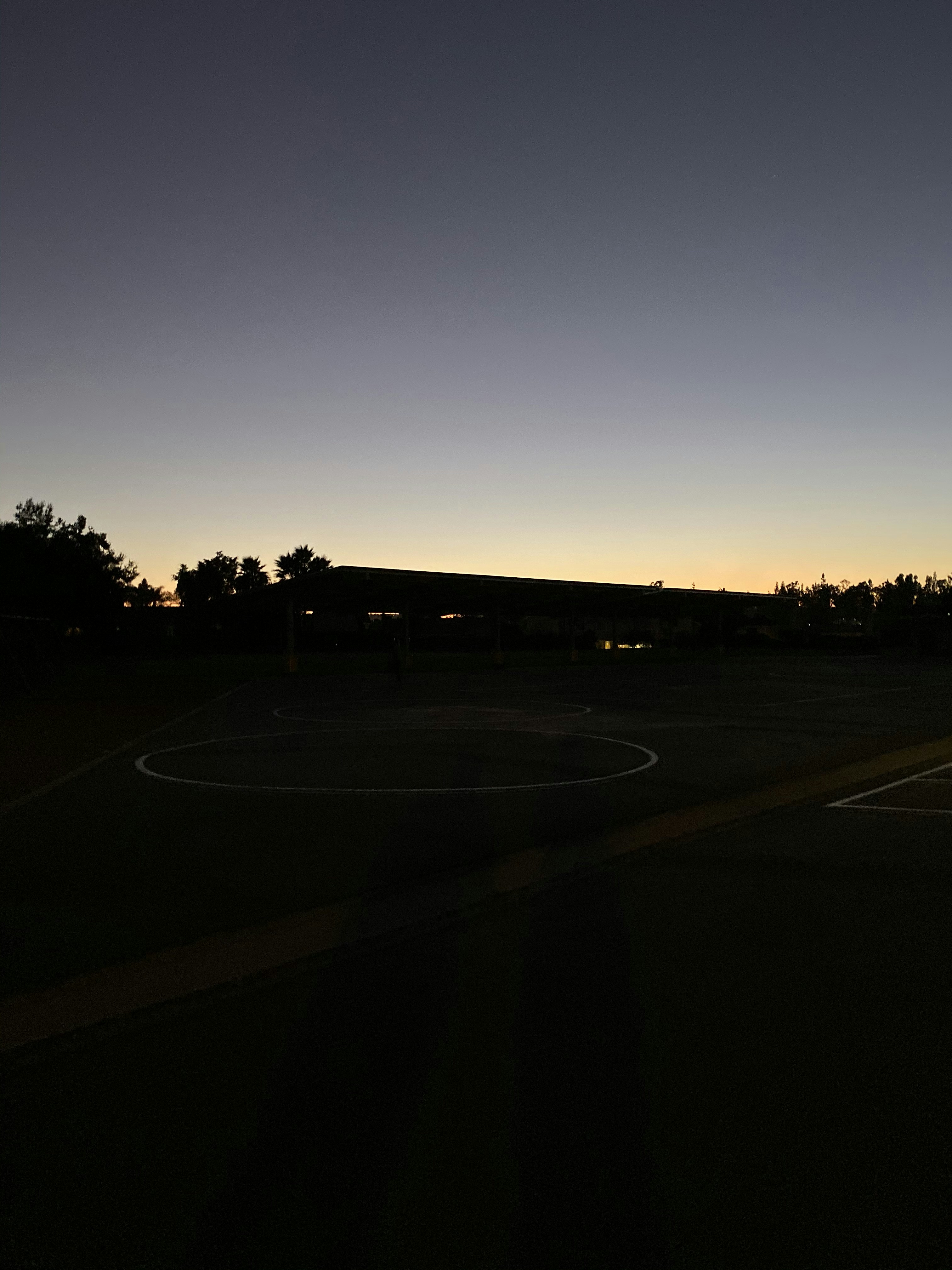 Basketball court with dramatic overhead lighting, dark gym environment, moody cinematic tone