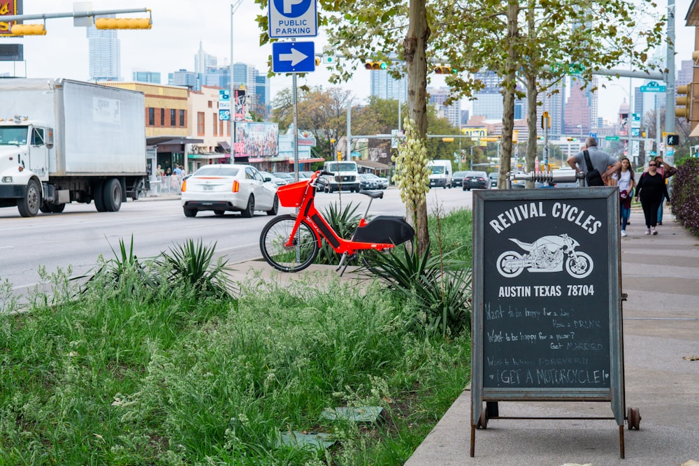 red and black bicycle parked on sidewalk near road sign during daytime