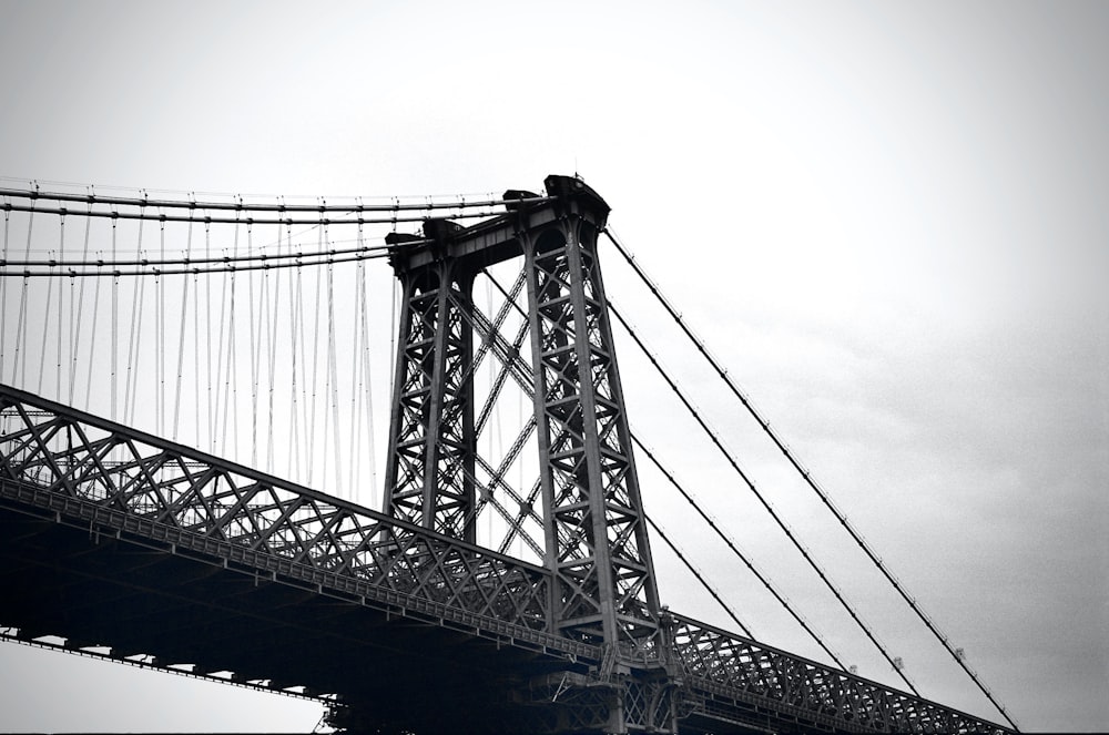 grayscale photo of bridge under cloudy sky