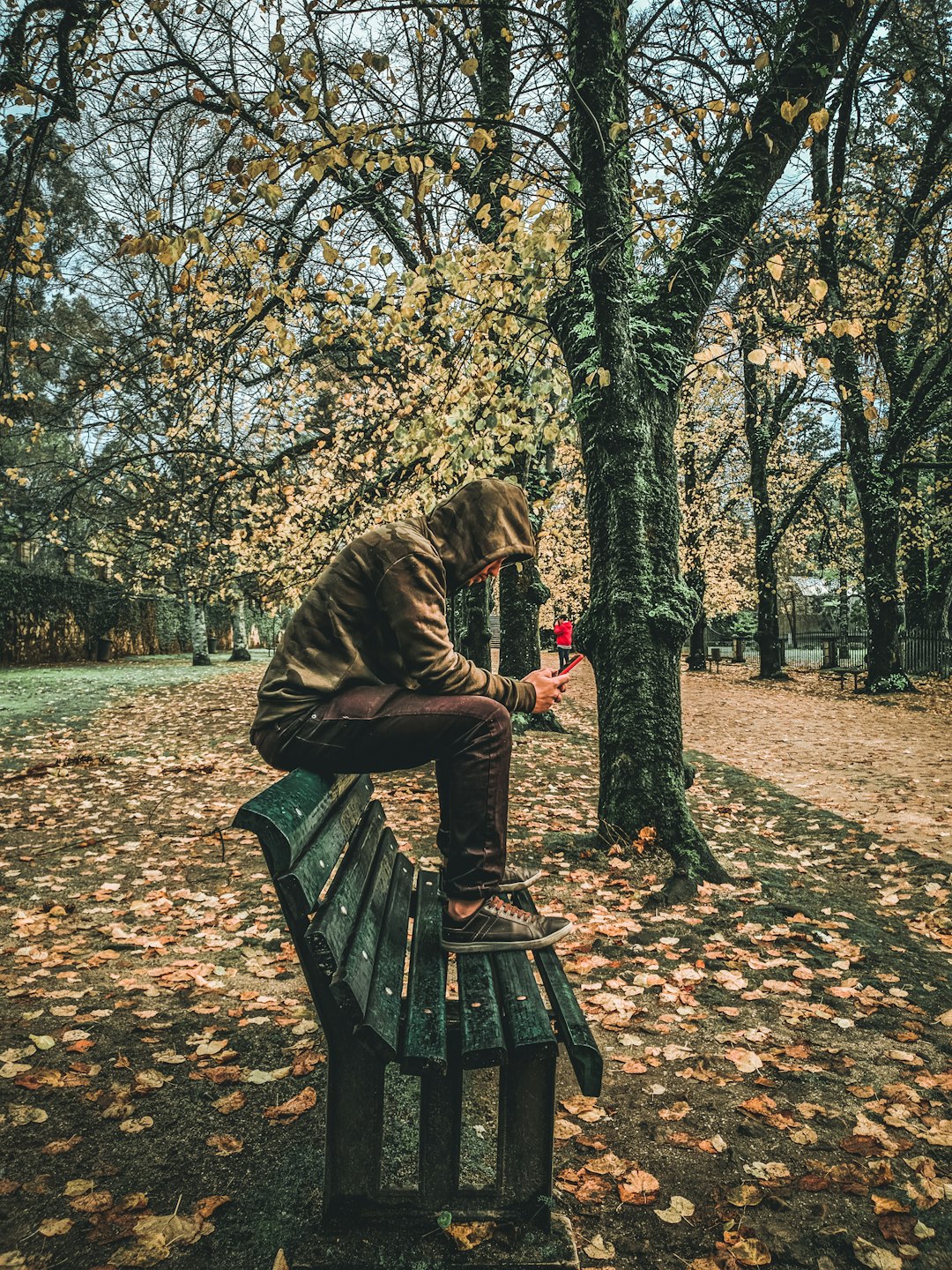 man in brown jacket sitting on brown wooden bench under brown tree during daytime