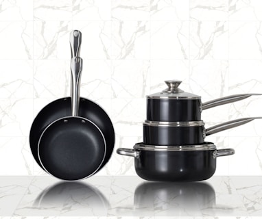 3 stainless steel cooking pots on white ceramic tiles