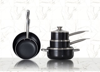 3 stainless steel cooking pots on white ceramic tiles