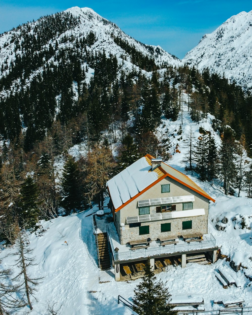 Casa di legno marrone su terreno innevato vicino alla montagna coperta di neve durante il giorno