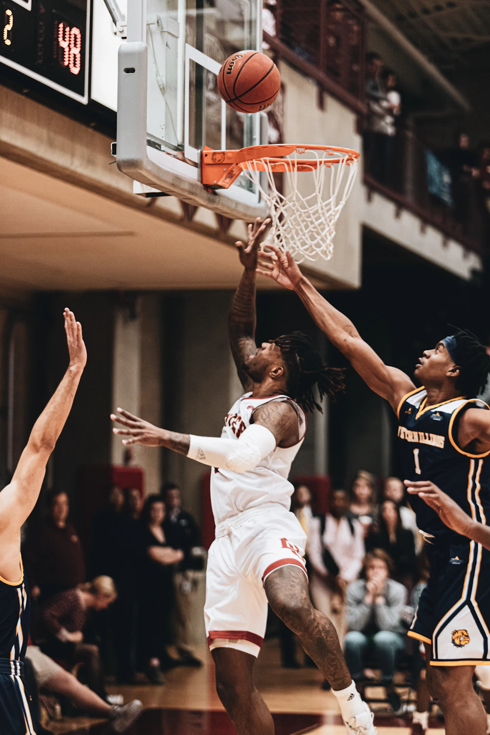 Basketball player attempting a layup against a defender in an indoor gym