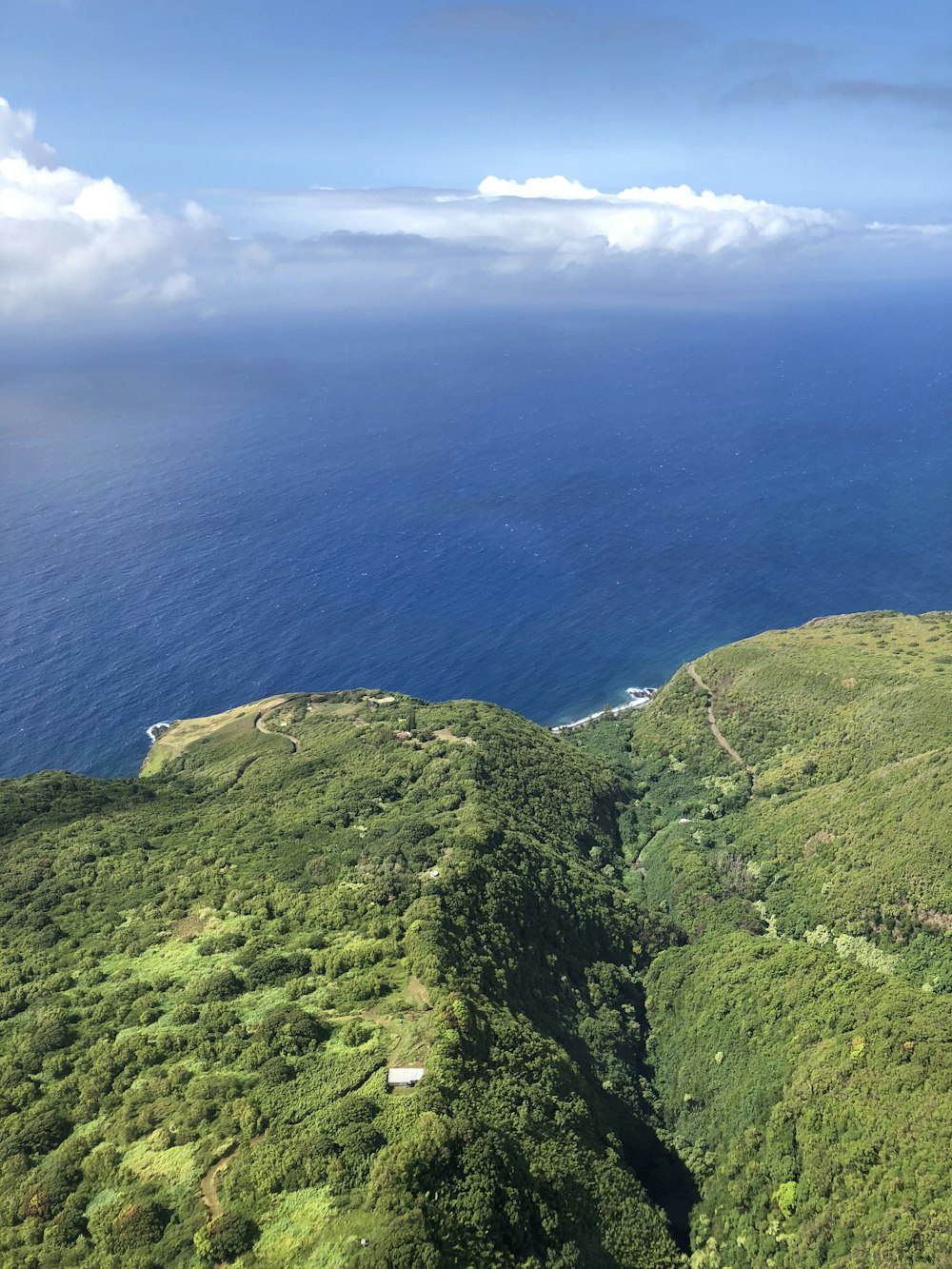 green mountain beside blue sea under blue sky during daytime