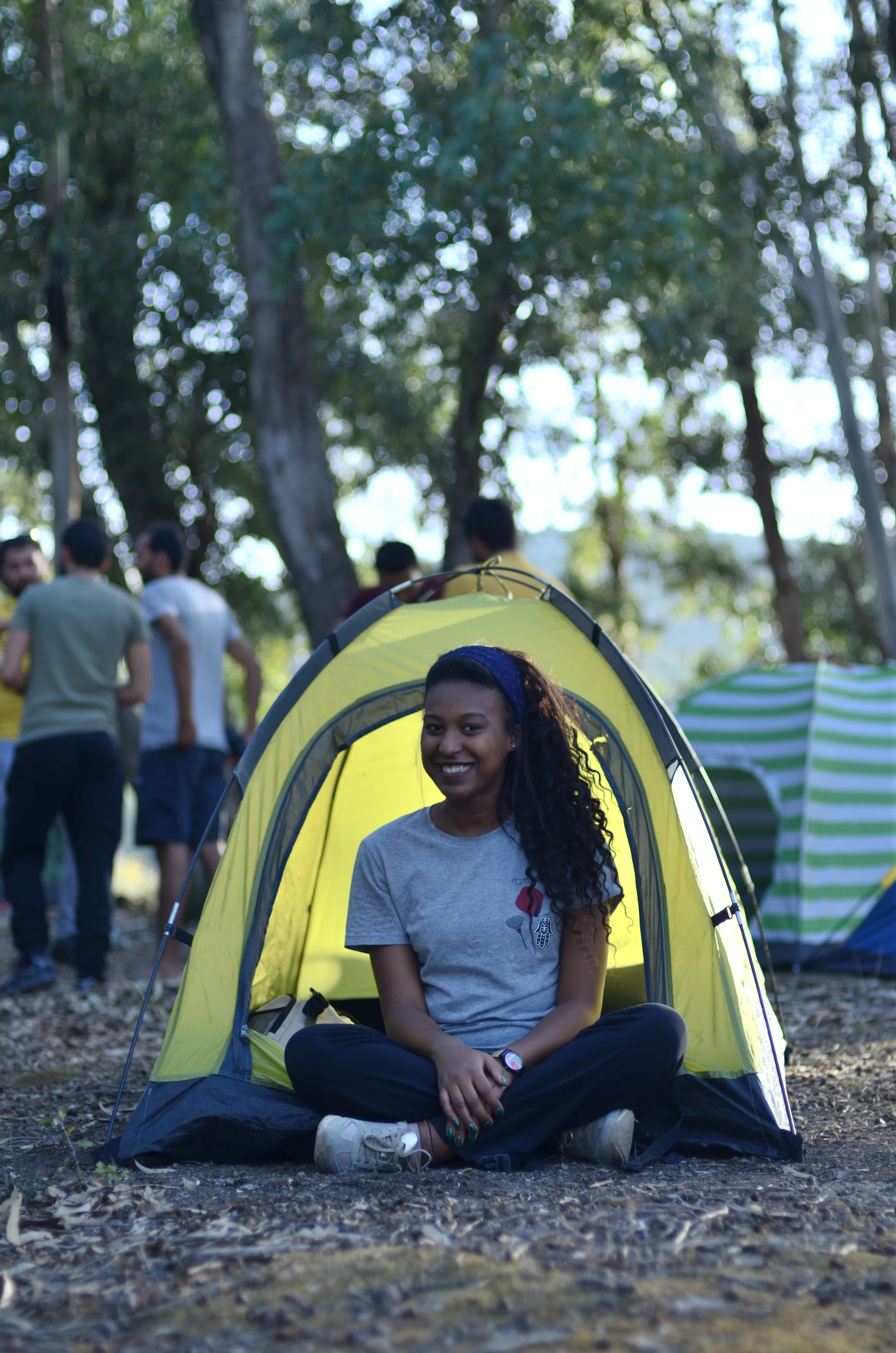 a woman sitting in front of a yellow tent
