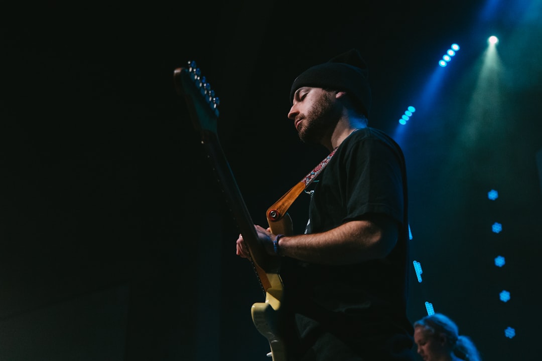 man in black t-shirt playing brown electric guitar