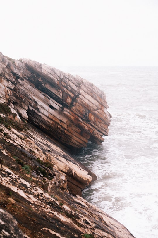 brown rock formation on sea water during daytime in Baleal Island Portugal