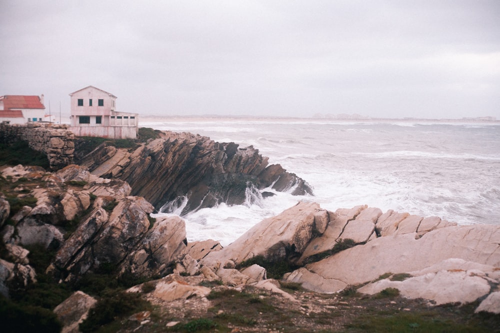 white and brown house on brown rocky shore near ocean water during daytime