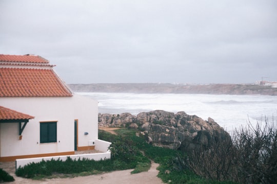 white and brown concrete house near body of water during daytime in Baleal Island Portugal