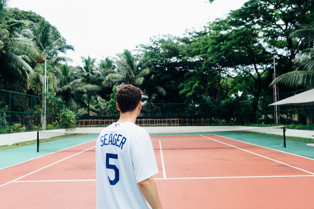 man in white and blue jersey shirt standing on track field during daytime