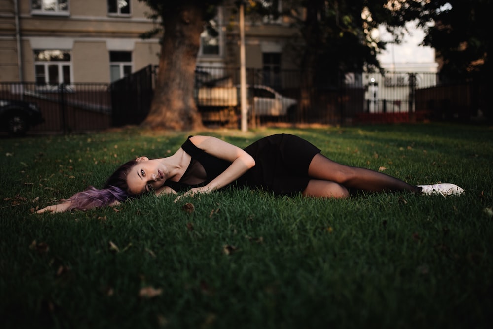 woman in black tank top lying on green grass field during daytime