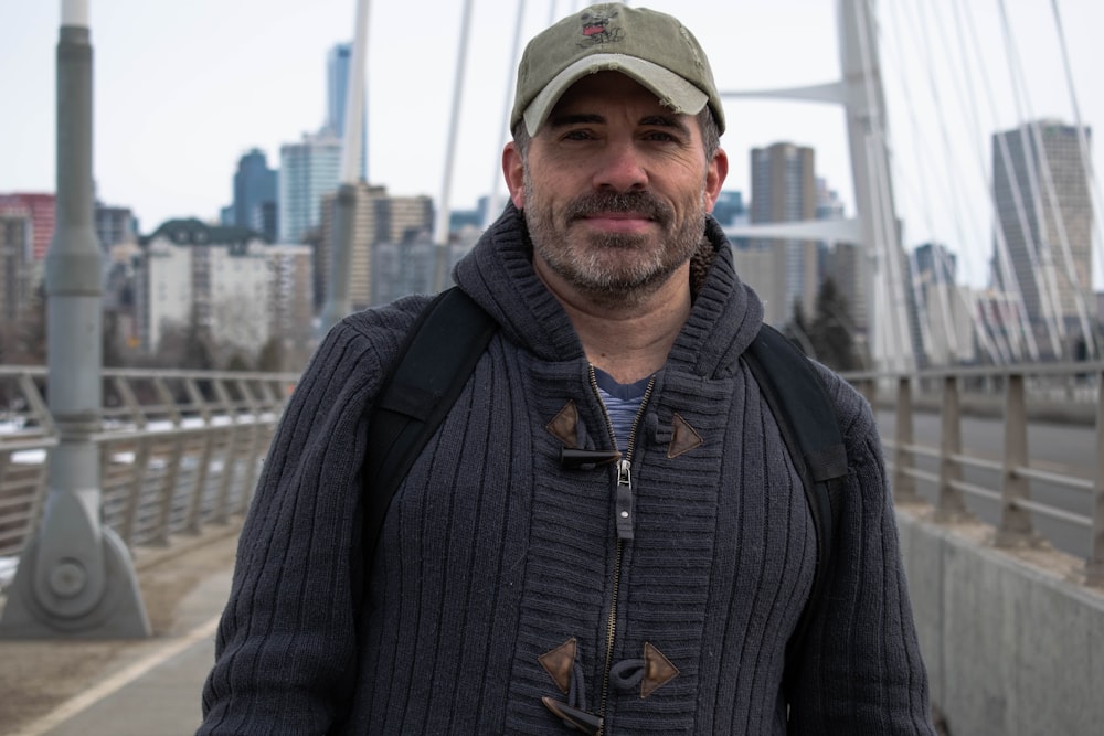 man in black zip up jacket and green cap