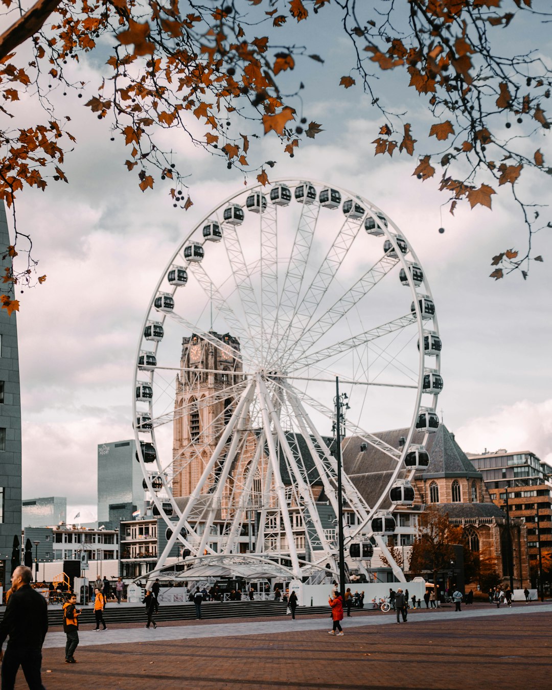 people walking on street near ferris wheel under cloudy sky during daytime