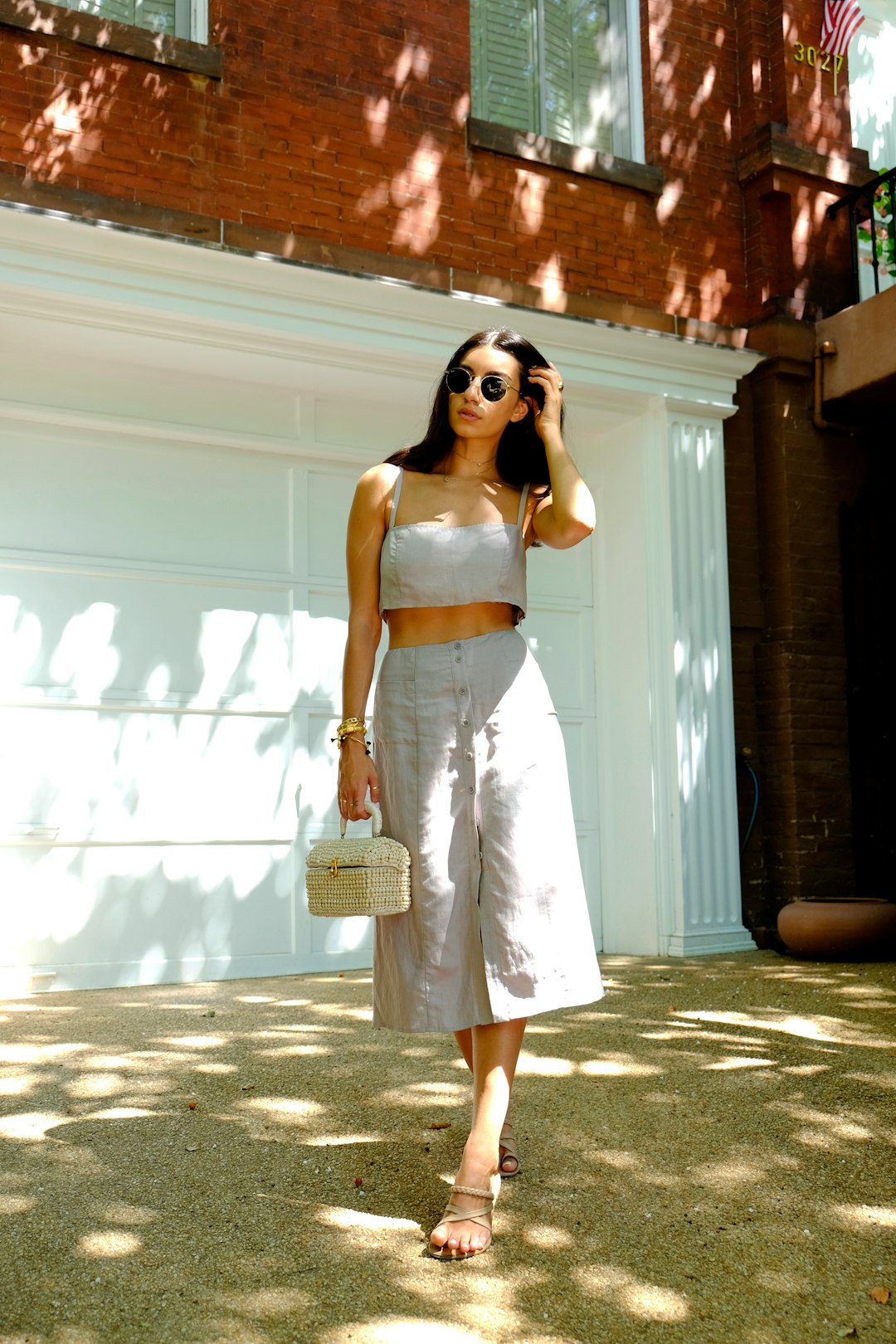 woman in white spaghetti strap dress wearing sunglasses standing near white wall during daytime