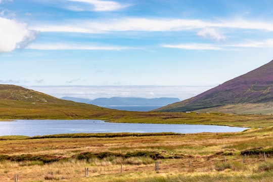 green grass field near mountain under white clouds during daytime in Donegal Ireland