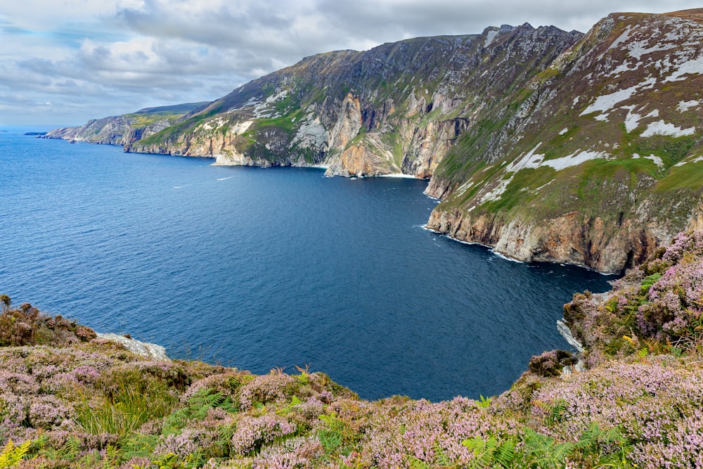 green and brown mountain beside body of water during daytime