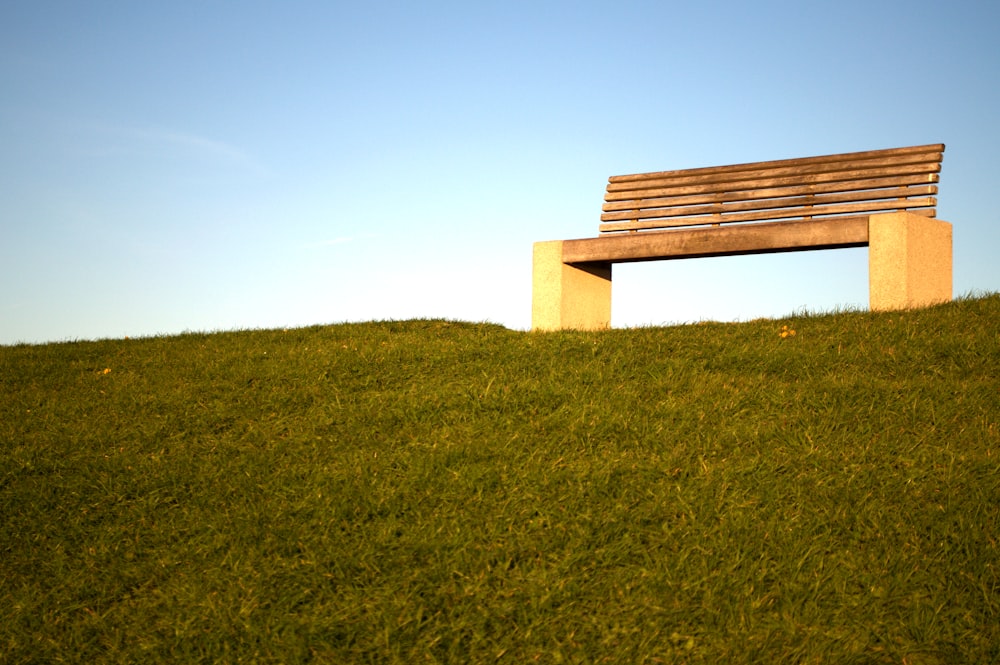 brown wooden bench on green grass field under blue sky during daytime