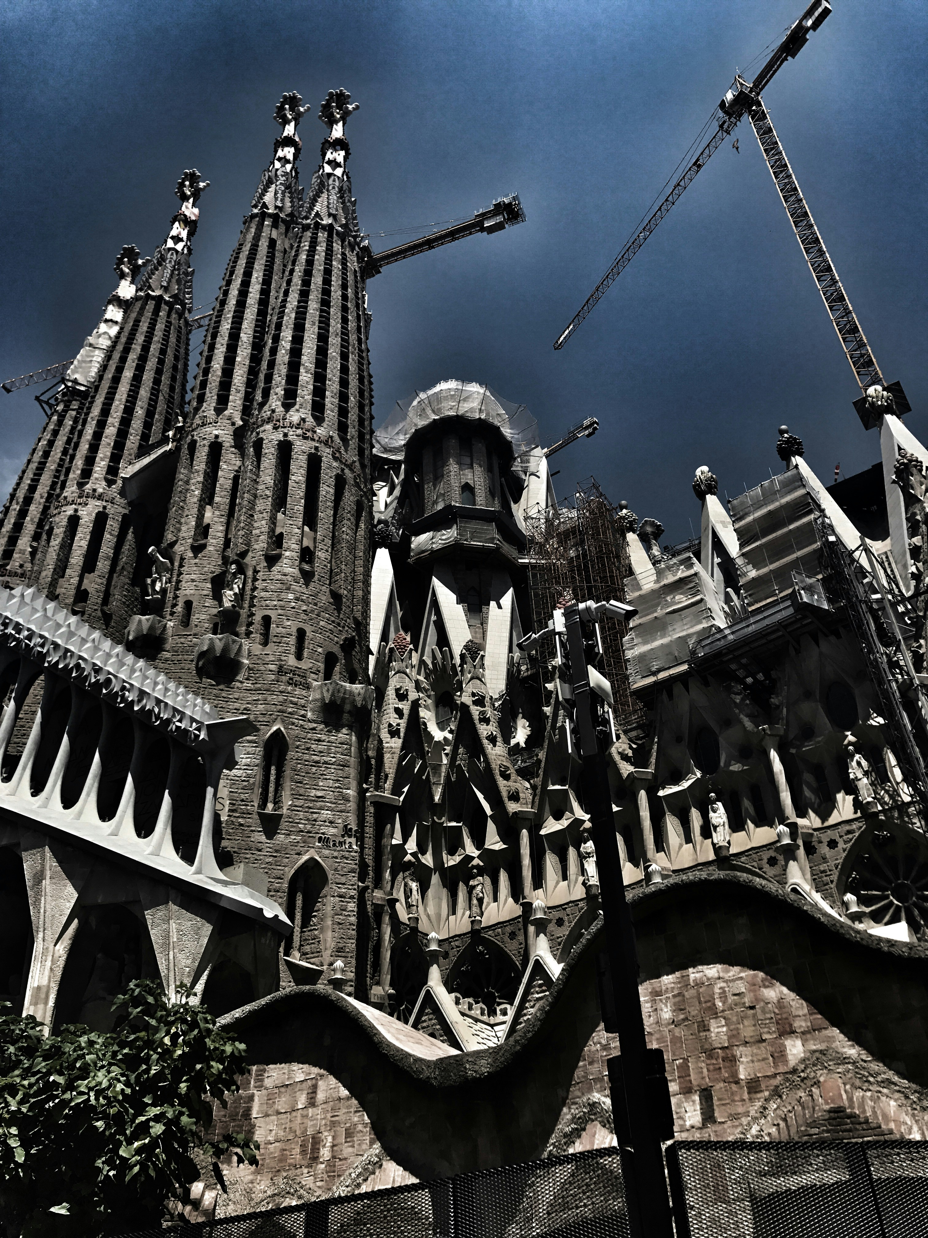 Sagrada Família de Gaudí al atardecer con cielo rosado, torres iluminadas, turistas en explanada