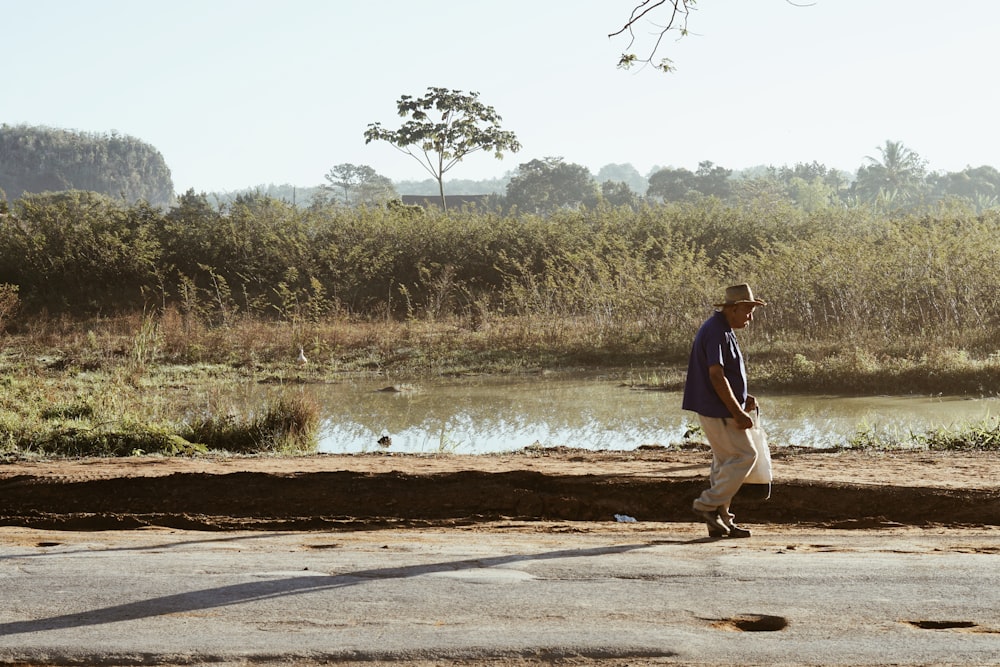 Hombre en chaqueta marrón caminando por camino de tierra marrón durante el día