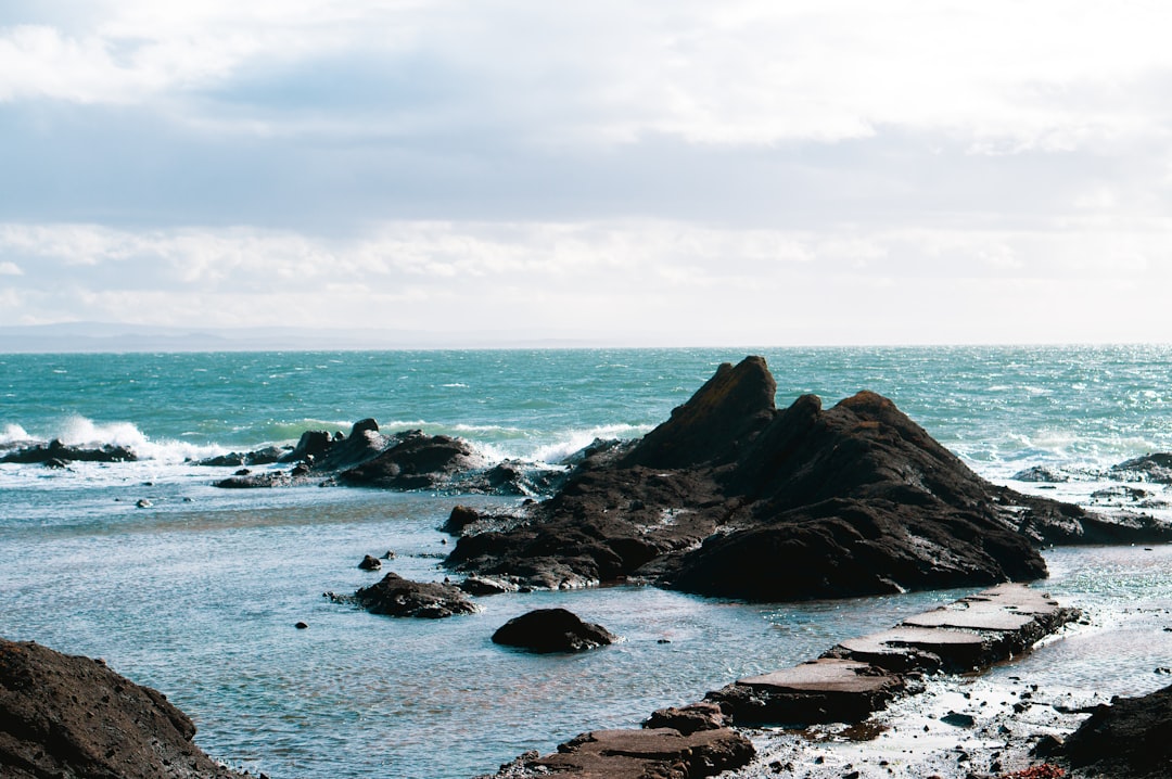 brown rock formation on sea under white clouds during daytime