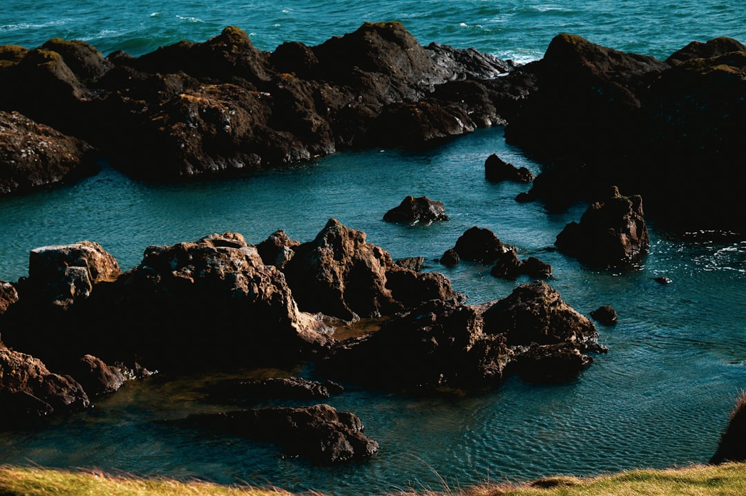 black rock formation on body of water during daytime