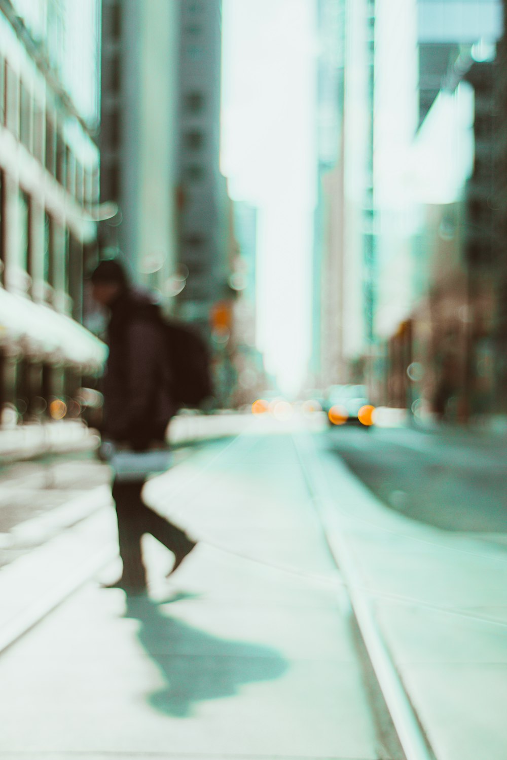 homem em jaqueta preta andando na calçada durante o dia