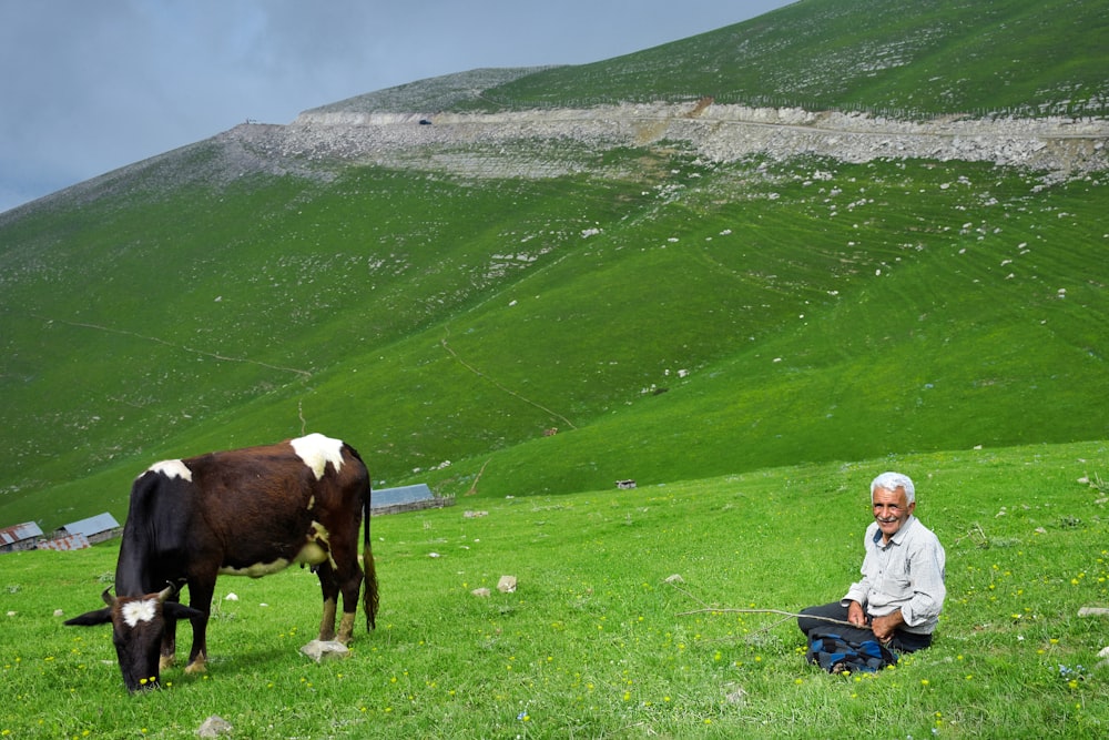 donna in giacca bianca che si siede sulla borsa blu del bagaglio sul campo dell'erba verde durante il giorno