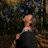 A smiling young woman standing in a sunlit forest, embodying hope and resilience.