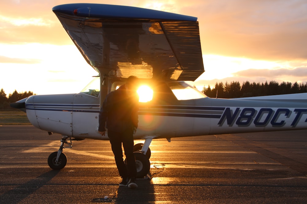 man in black jacket and black pants standing beside airplane