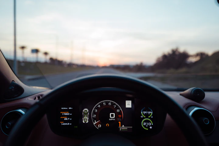 Volante de un coche con la carretera al atardecer
