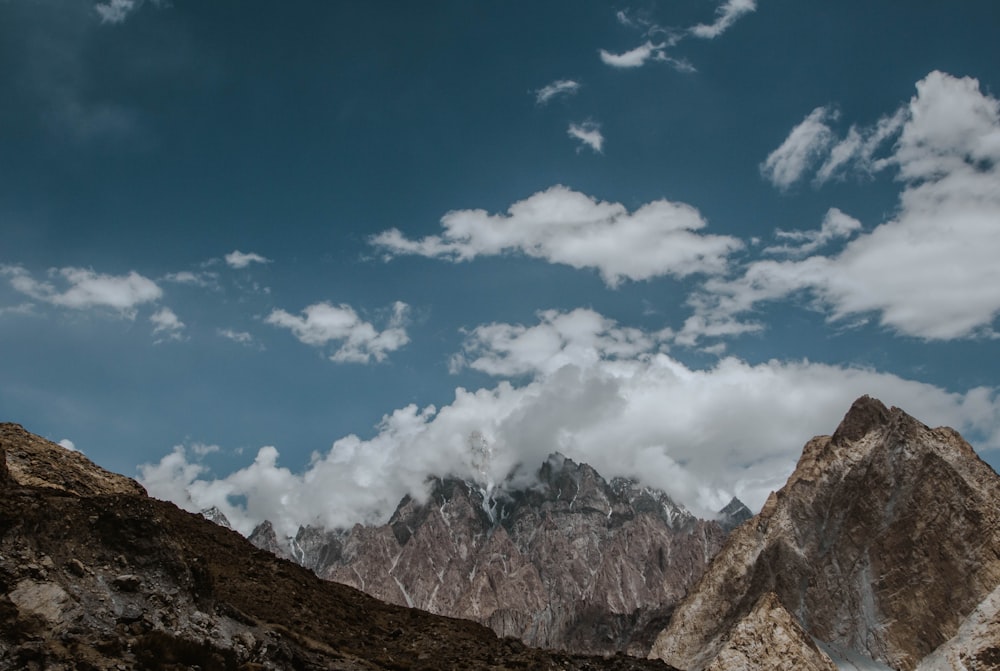 brown rocky mountain under blue sky and white clouds during daytime