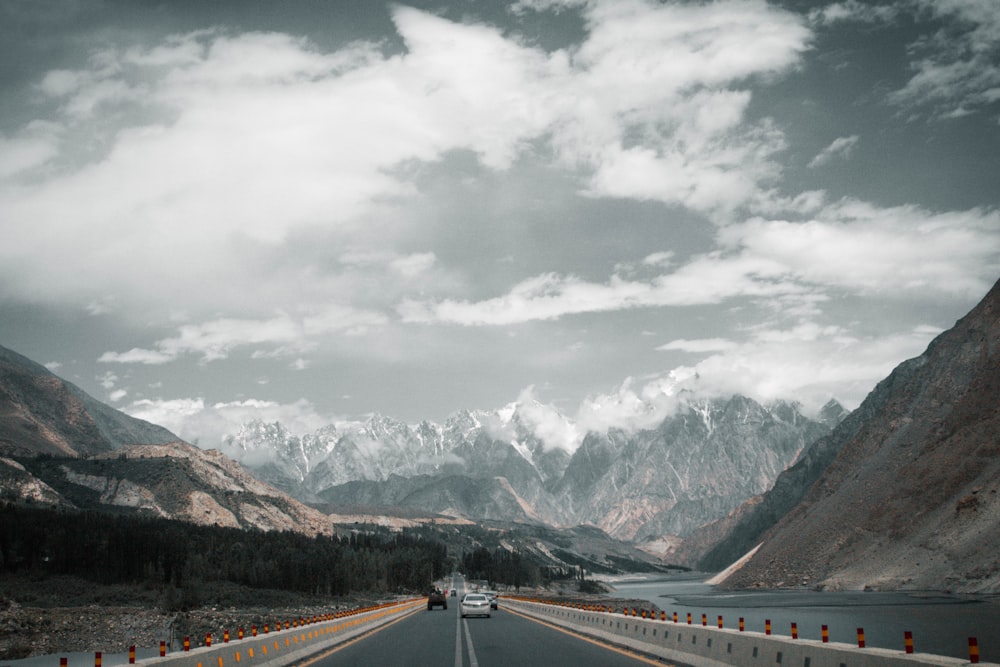 gray concrete road near mountain under white clouds during daytime