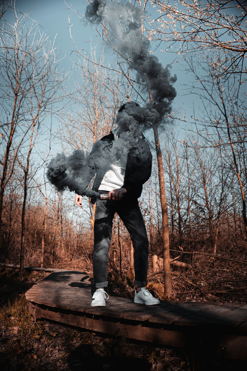 man in gray jacket and black pants standing on brown wooden log