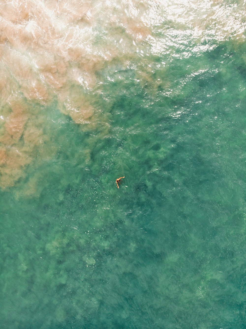 person swimming on body of water during daytime