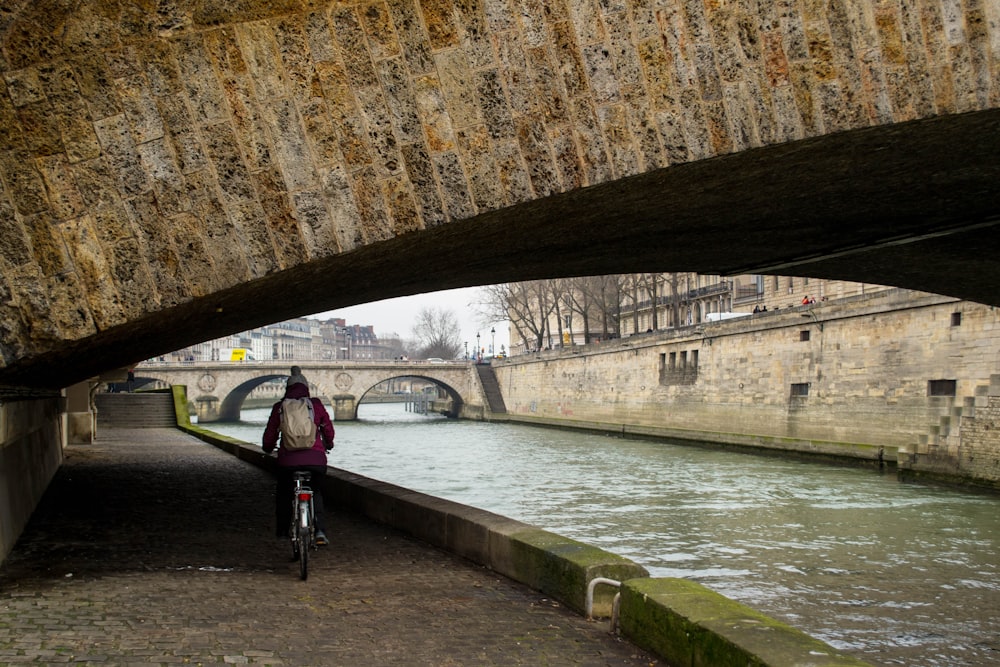 a person riding a bike under a bridge