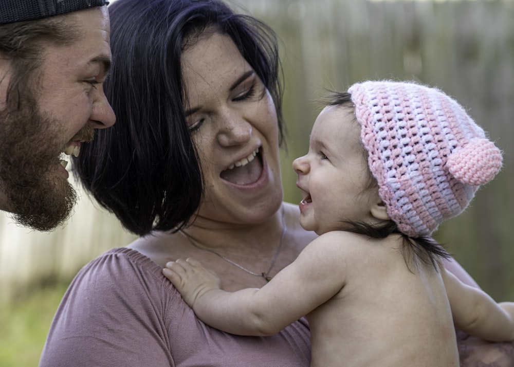 woman in pink knit cap carrying baby in pink knit cap