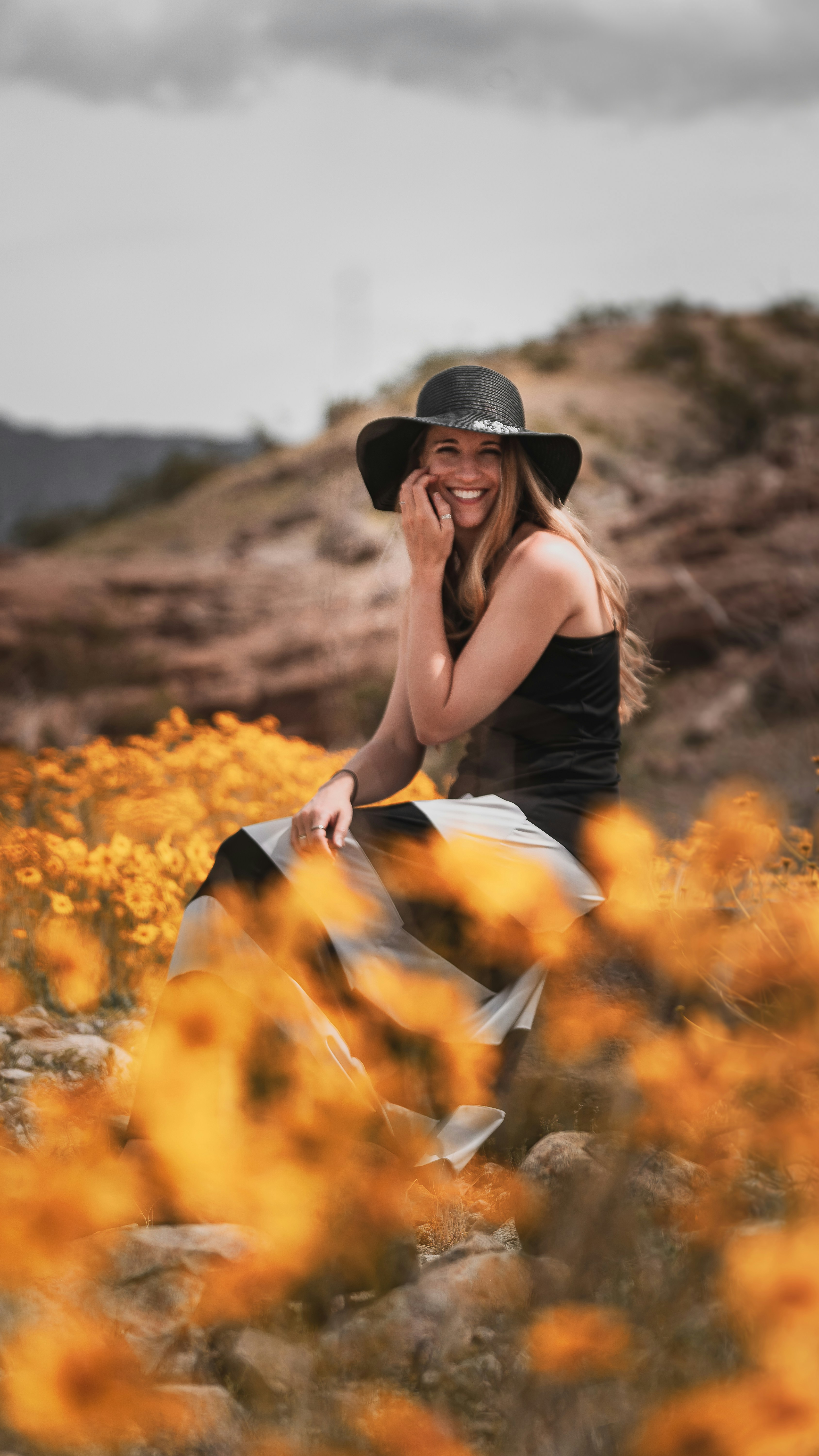 woman in black dress sitting on brown grass field during daytime