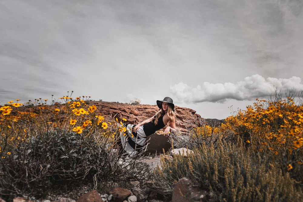 man in black and white shirt sitting on brown rock during daytime