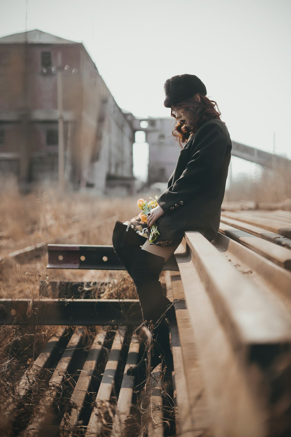 man in black suit sitting on brown wooden bench during daytime