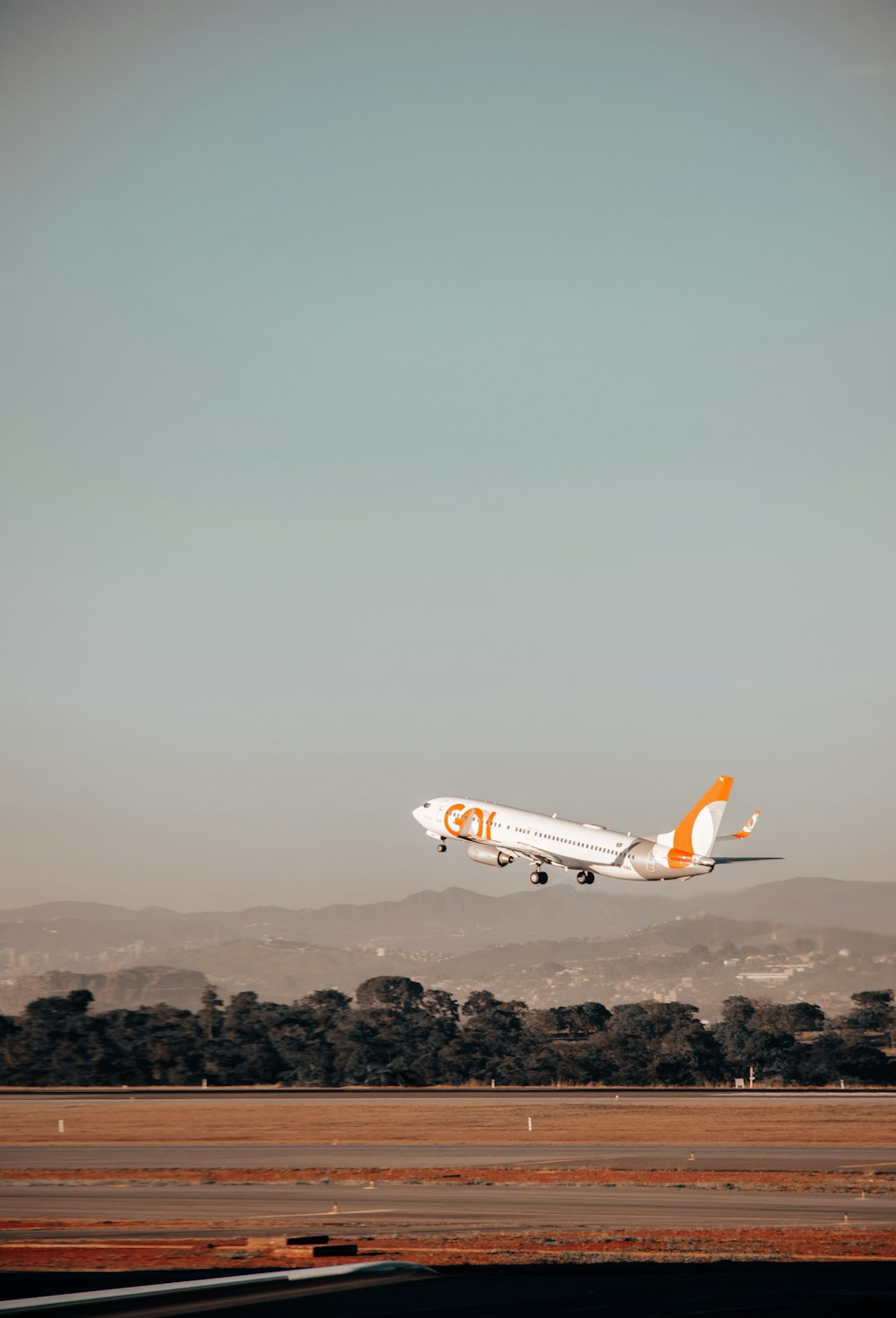 Avion blanc et orange en plein vol pendant la journée